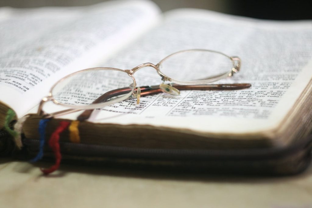 pexels-photo-273936 Close-up of eyeglasses atop an open Bible with colorful bookmarks, ideal for religious study themes.